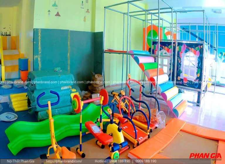 Khu vui chơi trong nhà đang lắp đặt: khung leo kim loại, bậc mềm nhiều màu, cầu trượt và xe chòi chân