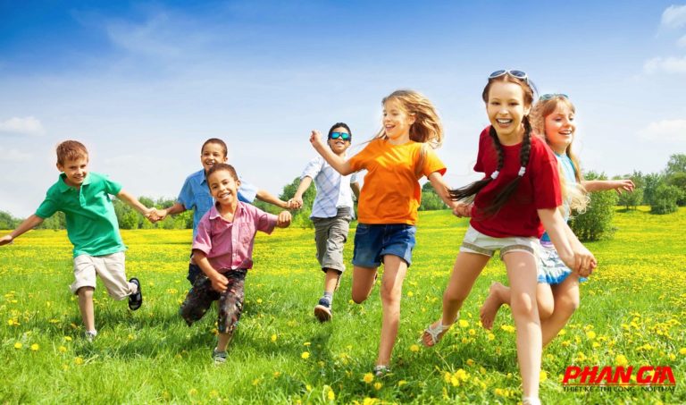 Trẻ mầm non chạy nhảy vui vẻ, nắm tay nhau trên cánh đồng hoa dại