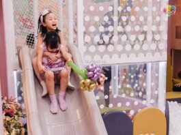 Lòng biết ơn là gì, Ý nghĩa và cách ứng dụng lòng biết ơn trong cuộc sống Hai bé gái ôm nhau trượt cầu trượt trong khu vui chơi, một bé cầm bó bong bóng hoa