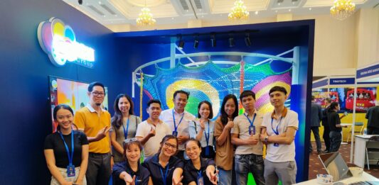 Triển lãm nghề công viên giải trí: không gian học nghề thực tế cho học sinh và giáo viên Nhóm người tham dự chụp ảnh trước gian hàng có mô hình lưới trò chơi màu sắc